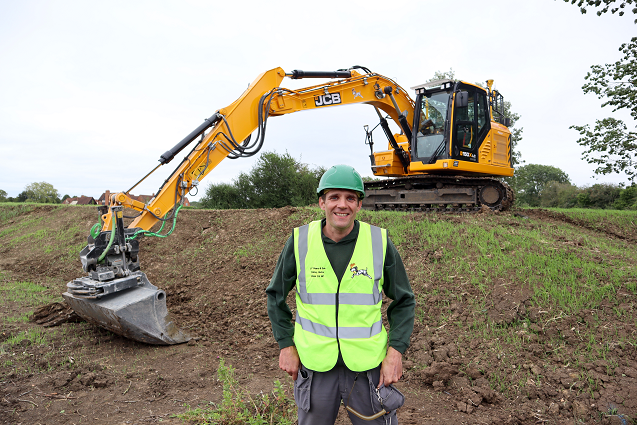 Derek Pearce is standing near the JCB backhoe.