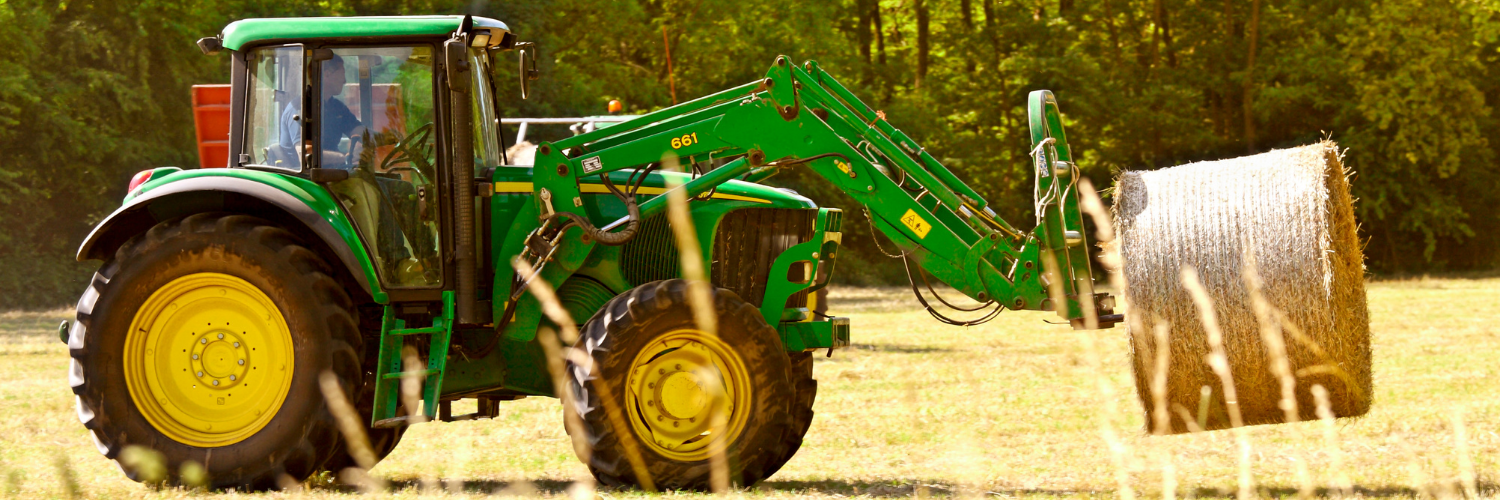 A side view of the agricultural machine, while moving hay bales.