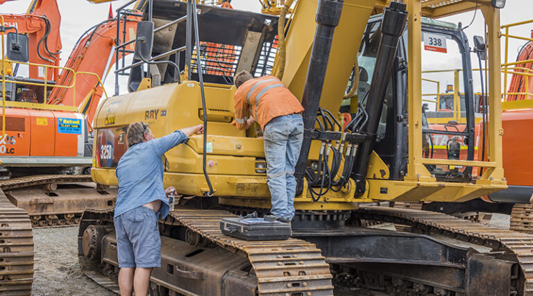 Two men are checking the heavy equipment/