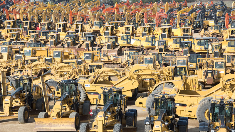 Different types of heavy equipment are being parked in the auction yard.