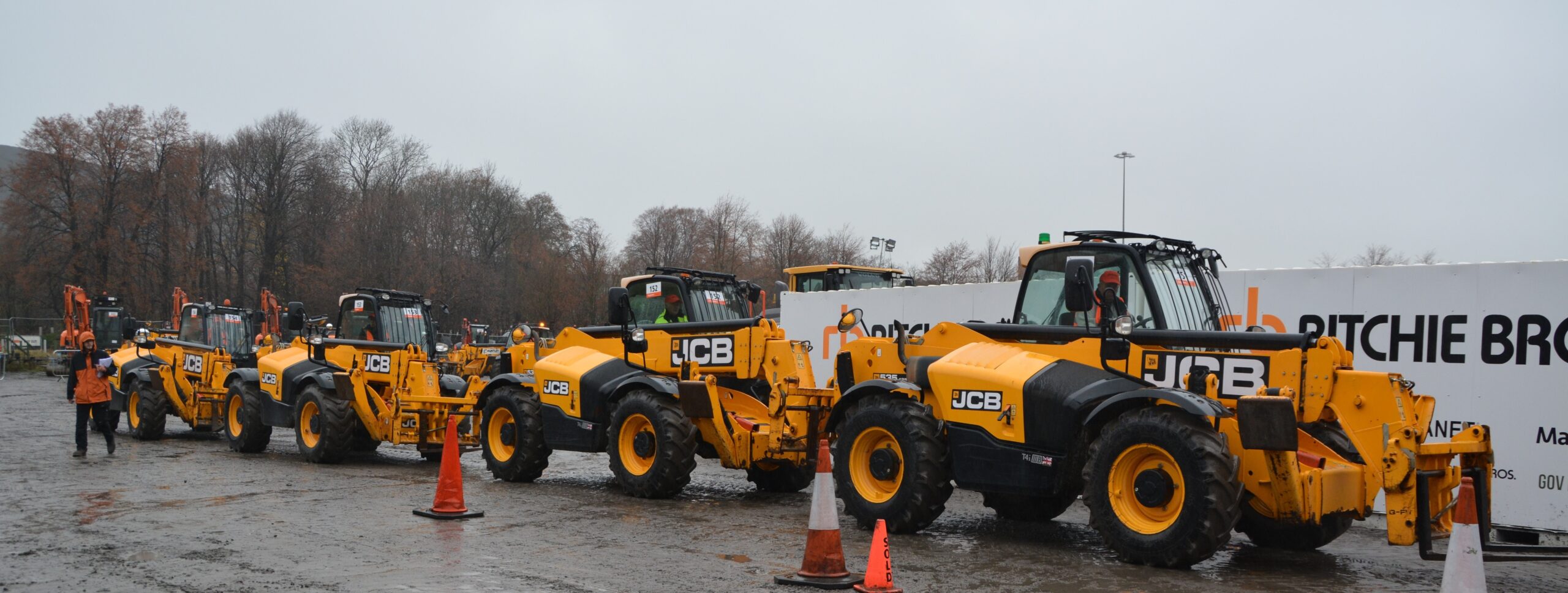 Several JCB Telehandlers are lined up in front of the RB auction yard.
