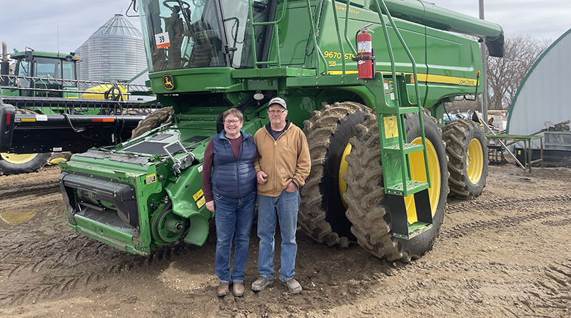 Man and woman are standing behind the heavy equipment.