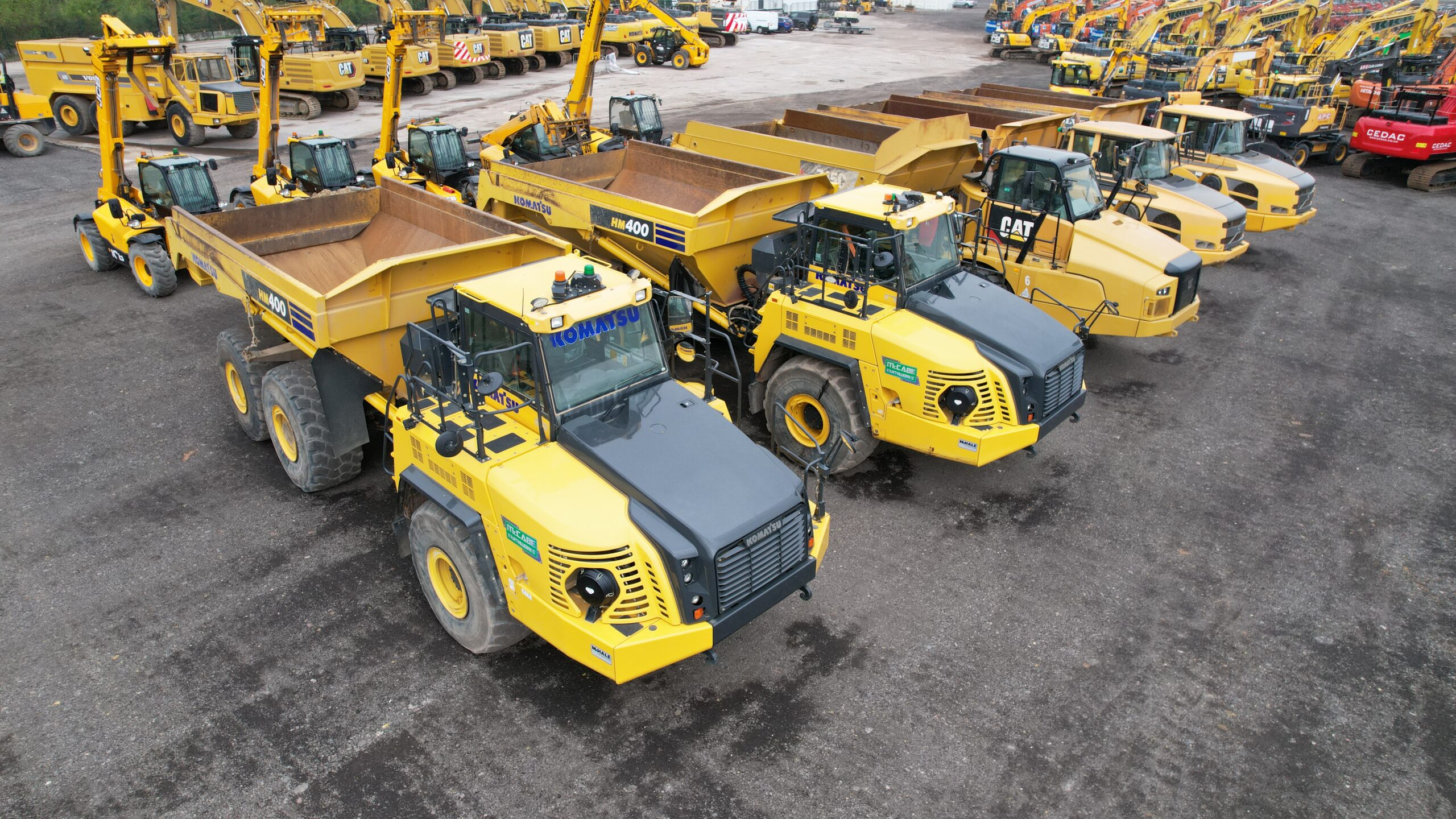 A group of Komatsu articulated dump trucks and other heavy-duty construction vehicles.
