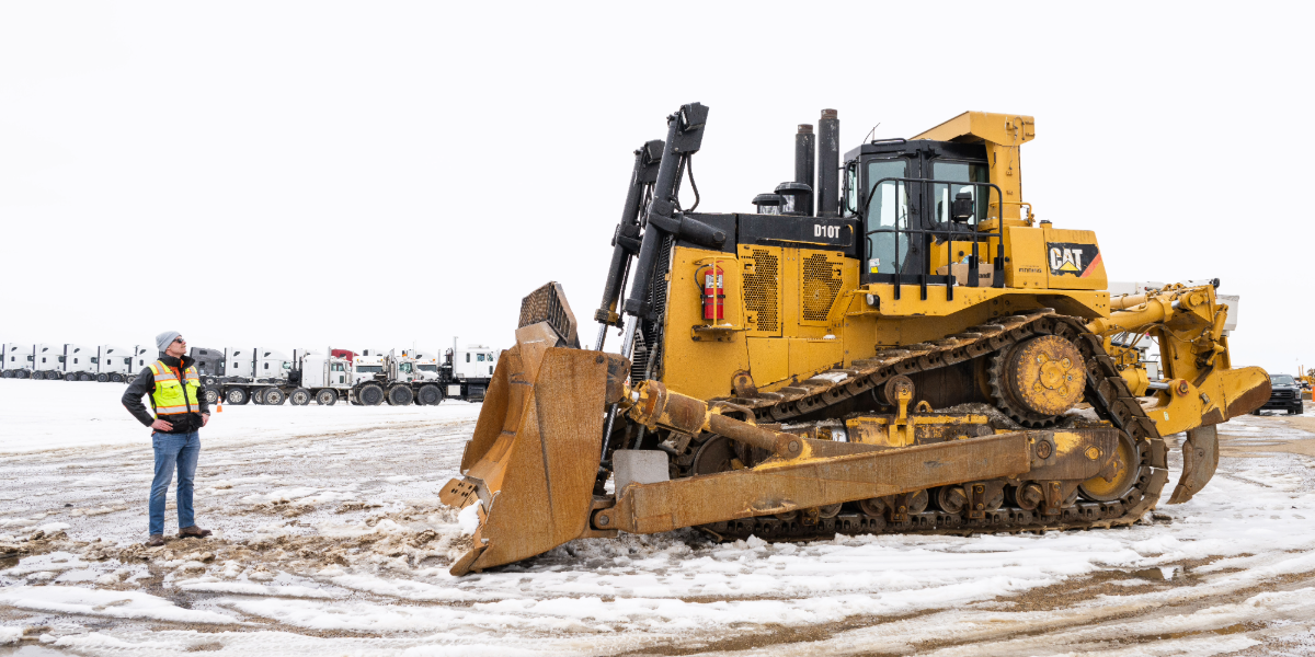 A man inspect a large Caterpillar bulldozer.