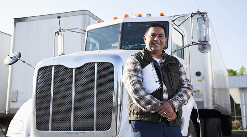 A man standing in front of semi truck with clipboard folder