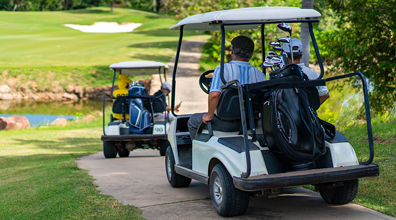 Two pairs of men are riding Golf carts.