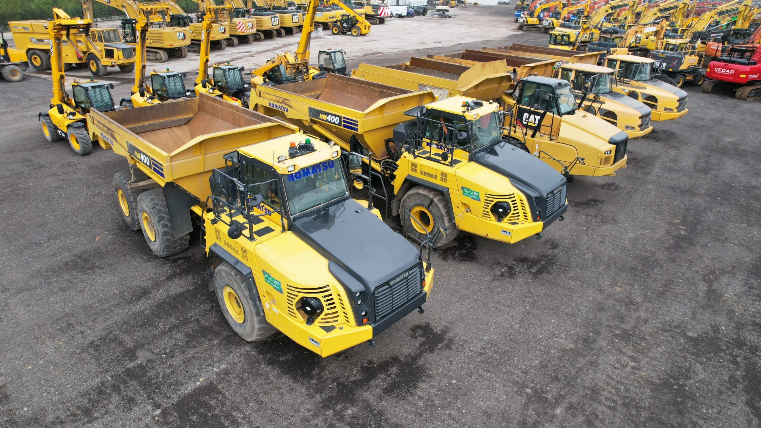 A group of Komatsu articulated dump trucks and other heavy-duty construction vehicles.